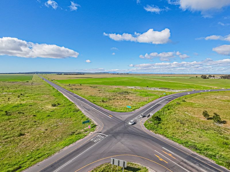 Aerial view of a rural road intersection surrounded by expansive open land and agricultural fields.