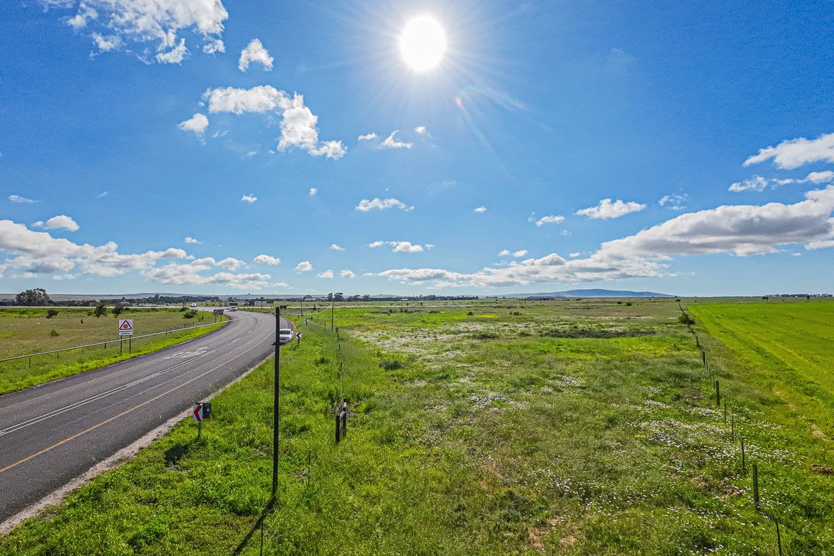 Aerial view of a large vacant commercial land parcel adjacent to a paved road with clear visibility and open landscape.