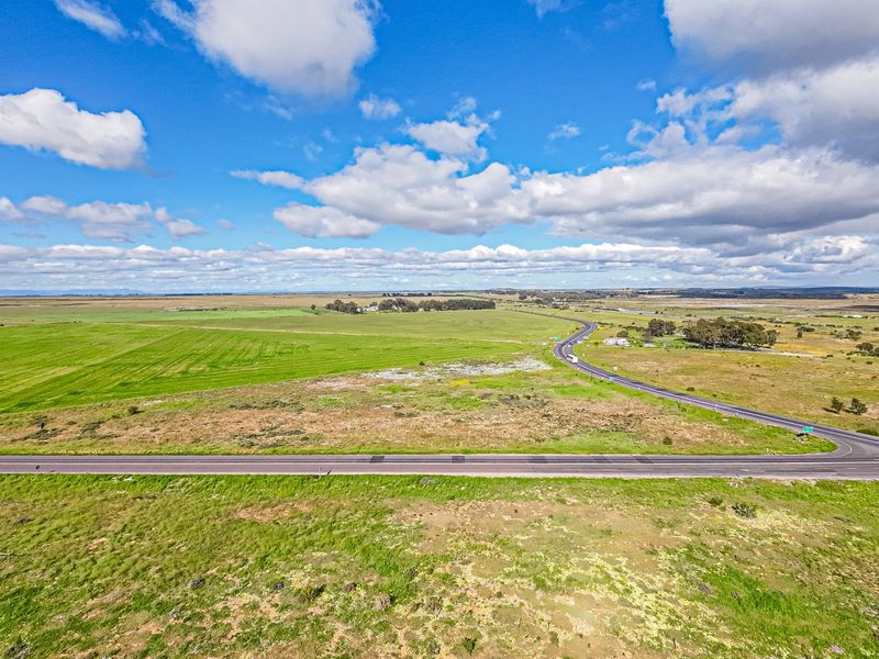 An aerial view of a large expanse of vacant commercial land adjacent to a paved road.