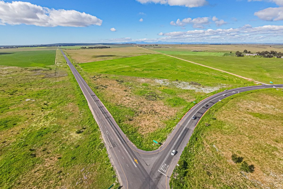 Aerial view of a large vacant commercial land parcel situated at a road intersection, offering extensive open space and accessibility.