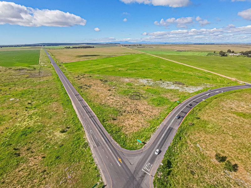 Aerial view of a large vacant commercial land parcel situated at a road intersection, offering extensive open space and accessibility.