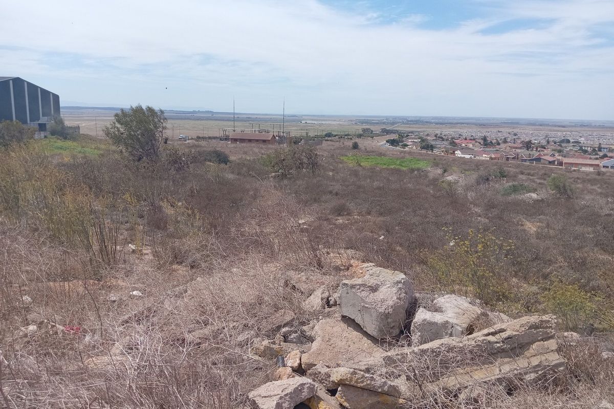 An elevated view overlooking a large expanse of undeveloped commercial land with surrounding residential areas in the distance.