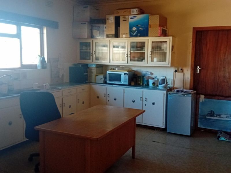 A dated kitchen area featuring original built-in cabinetry, a stainless steel sink, and tiled backsplash, offering potential for modernization and renovation.