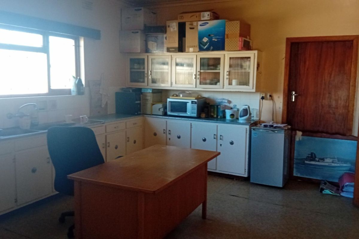 A dated kitchen area featuring original built-in cabinetry, a stainless steel sink, and tiled backsplash, offering potential for modernization and renovation.