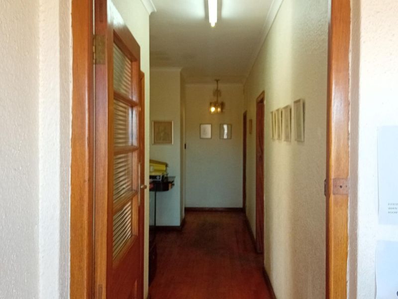 A functional commercial hallway featuring timber flooring and wooden door frames, providing access to multiple rooms within the property.