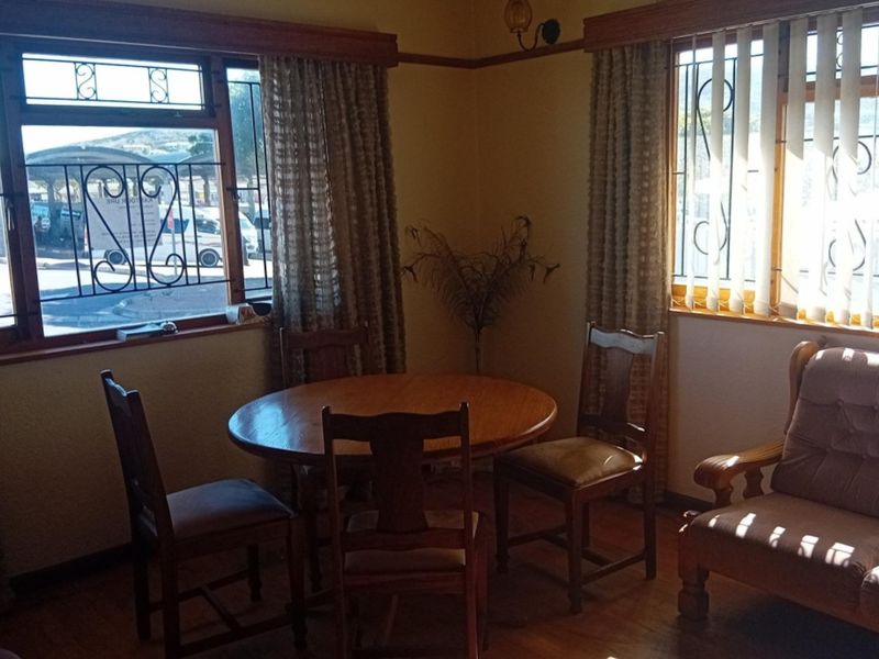 A living area featuring timber flooring, timber window frames with security burglar bars, and a classic picture rail detail.