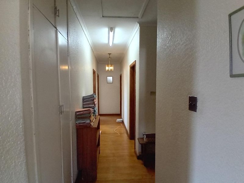A functional hallway featuring timber flooring, built-in storage cupboards, and overhead lighting, providing access to multiple rooms within the commercial property.