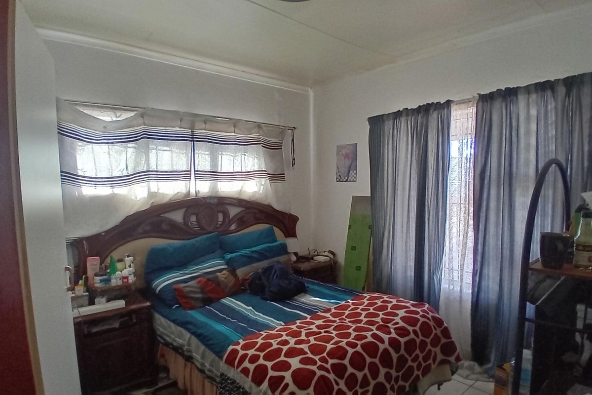 A bedroom featuring tiled flooring and windows fitted with security bars, requiring cosmetic updates to improve the overall condition of the space.