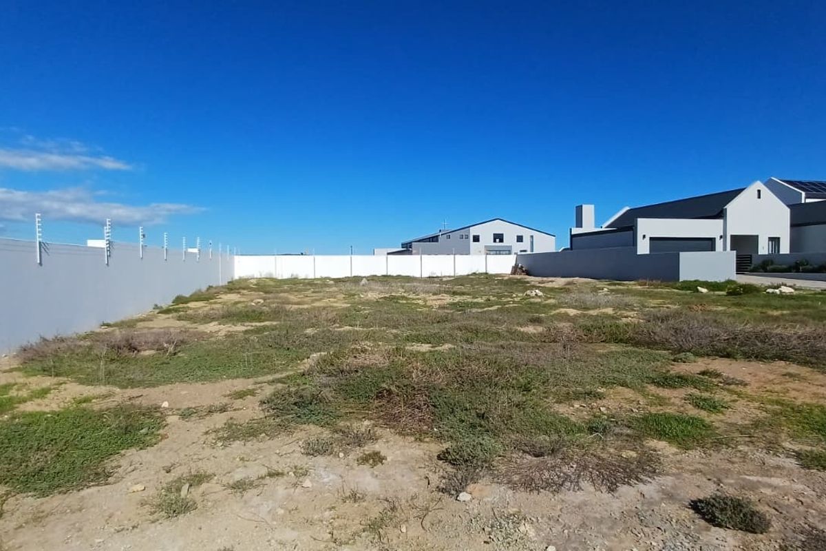 A vacant residential plot featuring a perimeter wall with electric fencing, situated in a developed neighborhood.