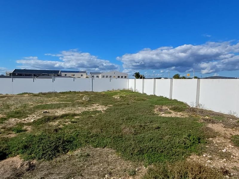 A vacant residential plot featuring a clean perimeter wall with installed electric fencing, ready for development.