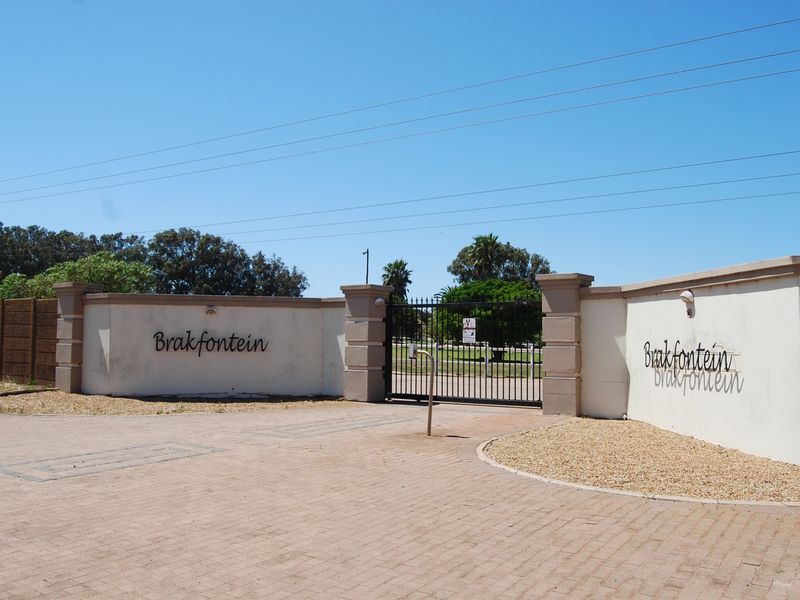 The main entrance to the Brakfontein small holding, featuring a secure wrought iron gate, masonry boundary walls, and a paved driveway approach.
