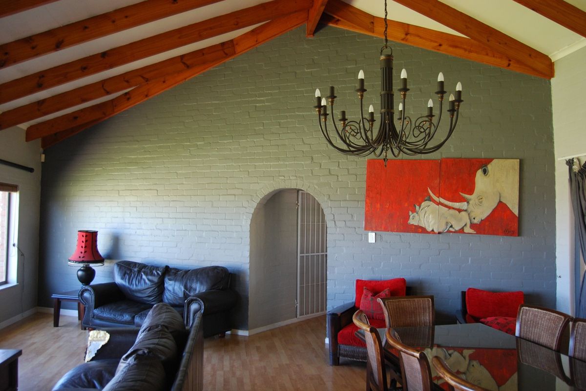 Spacious living area featuring a vaulted ceiling with exposed timber beams, a painted brick feature wall, and an elegant arched doorway.