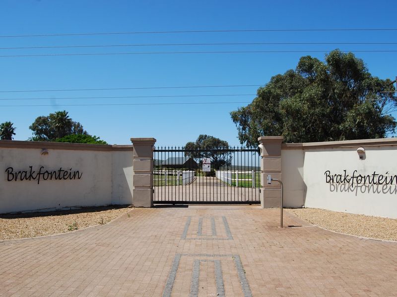 The main entrance to the Brakfontein small holding, featuring a secure gated access point, paved driveway, and perimeter walling.