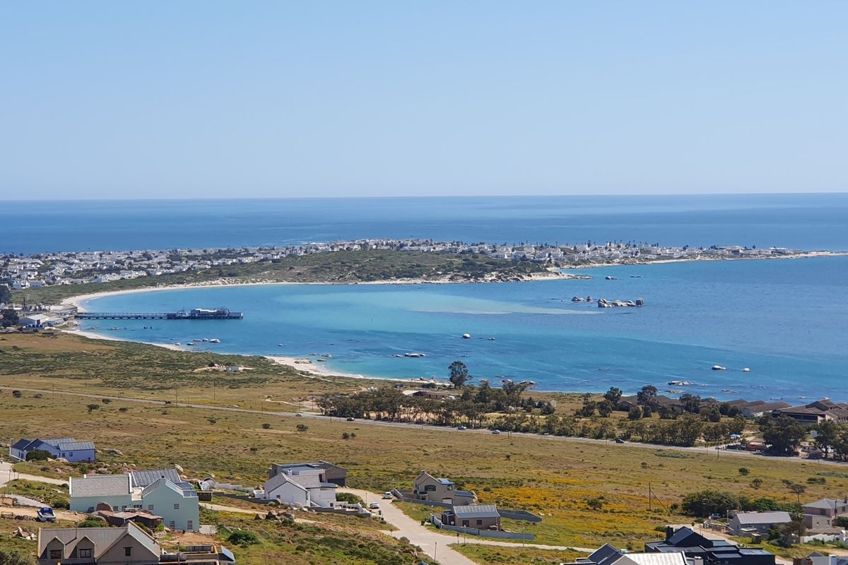 A panoramic elevated view overlooking the coastal landscape, featuring the ocean, sandy beach, and surrounding residential development.