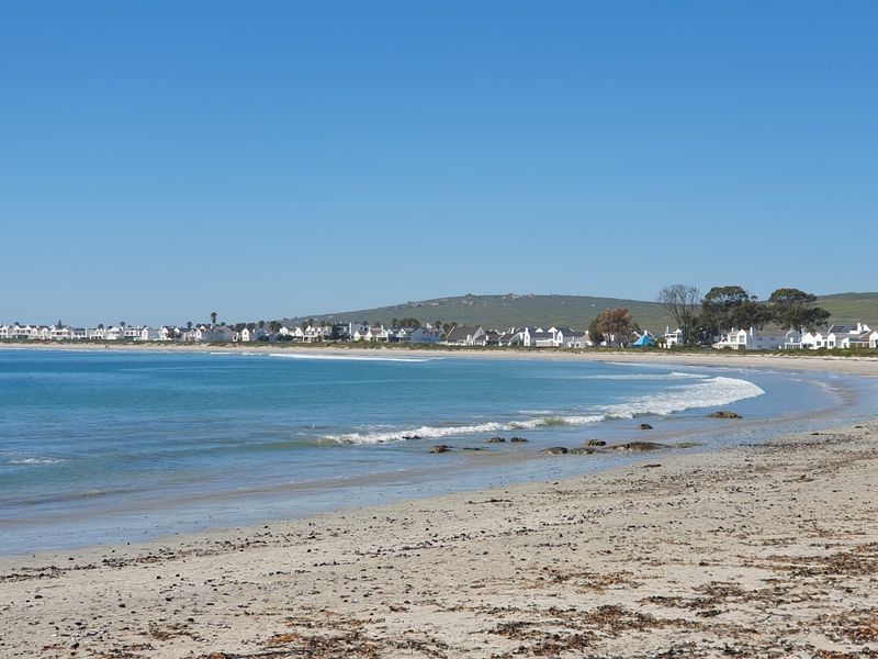 A scenic view of the sandy coastline and ocean, showcasing the surrounding residential neighborhood and natural landscape.