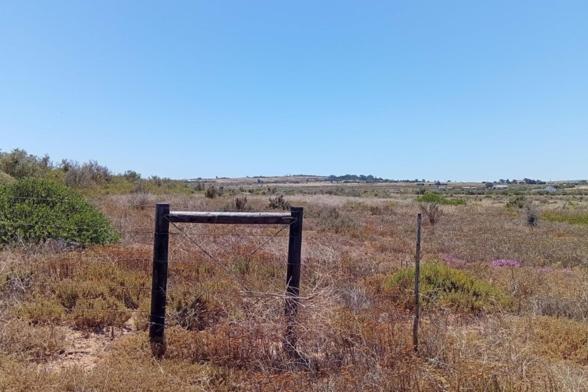 A view of a vacant residential plot featuring natural vegetation and perimeter wire fencing.
