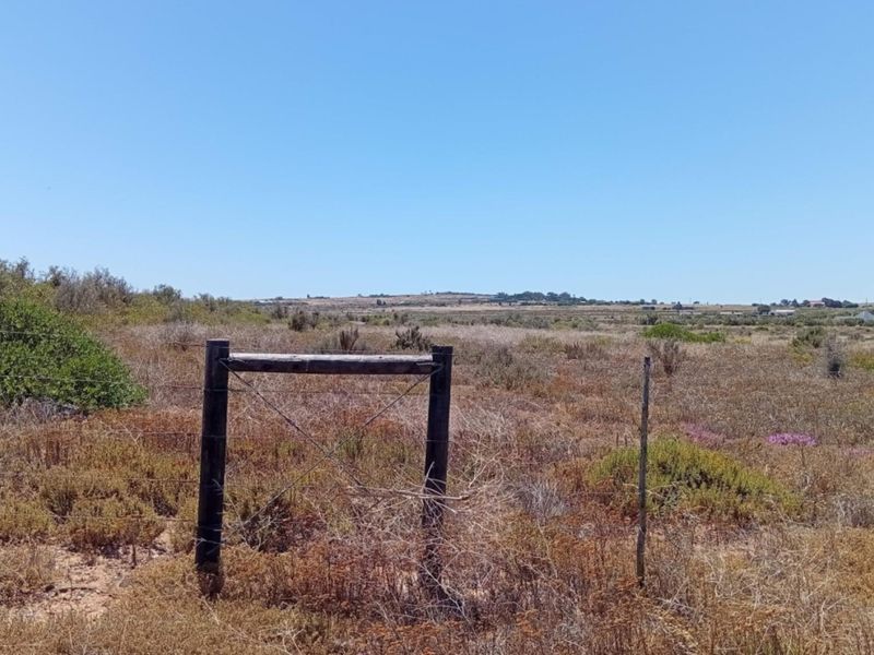 A view of a vacant residential plot featuring natural vegetation and perimeter wire fencing.