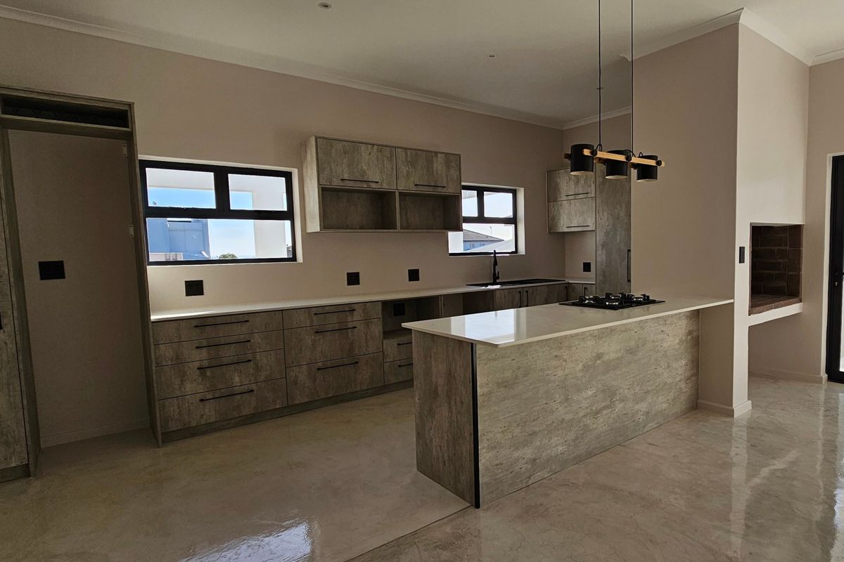 Modern open-plan kitchen featuring textured cabinetry, stone countertops, gas hob, and a built-in indoor braai area, finished with polished concrete flooring.