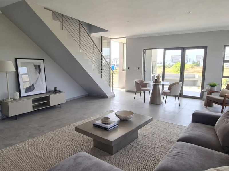 Spacious open-plan living area featuring modern tiled flooring, a sleek staircase with stainless steel balustrades, and large sliding doors leading to the outdoors.