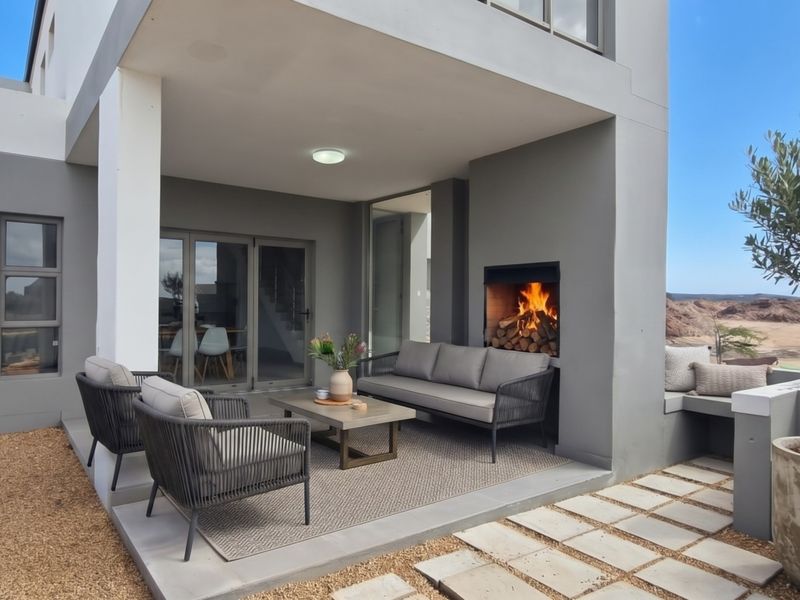 A modern covered patio featuring a built-in fireplace, concrete paving, and seamless access to the interior through large sliding glass doors.