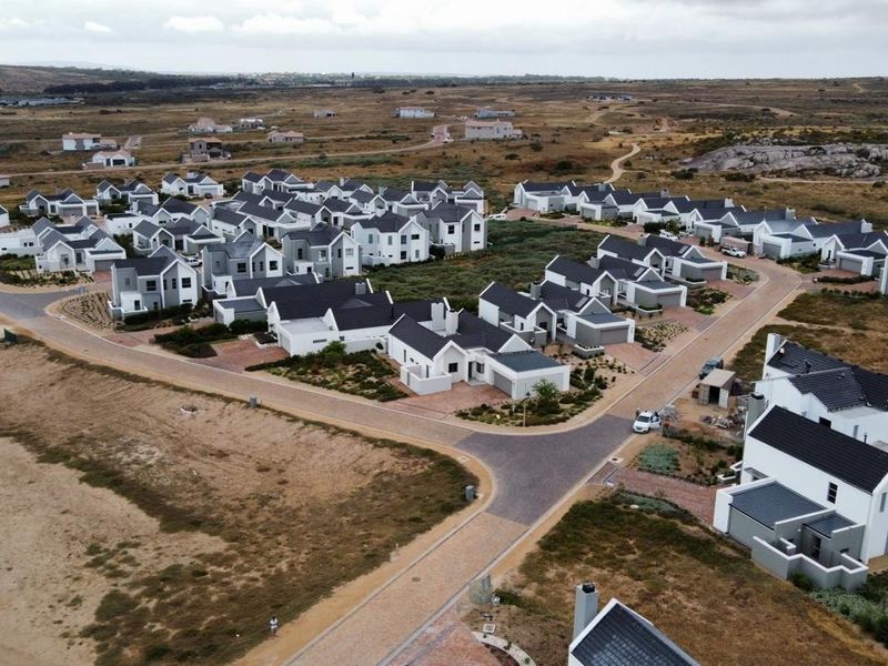 An aerial view of a modern residential housing estate featuring uniform architectural styles with pitched roofs and paved road infrastructure.