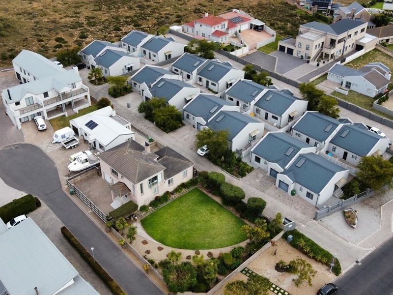 An aerial view of a residential estate featuring multiple detached homes with pitched roofs, paved driveways, and landscaped garden areas.
