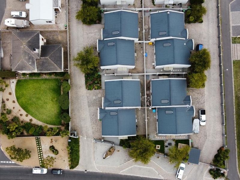 An aerial view of a residential estate featuring multiple detached houses with pitched roofs, paved driveways, and established garden areas.