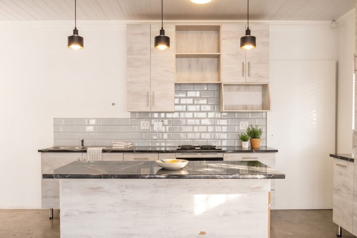 Modern kitchen featuring light wood-grain cabinetry, a dark stone-topped island, subway tile backsplash, and contemporary pendant lighting in a clean, open space.