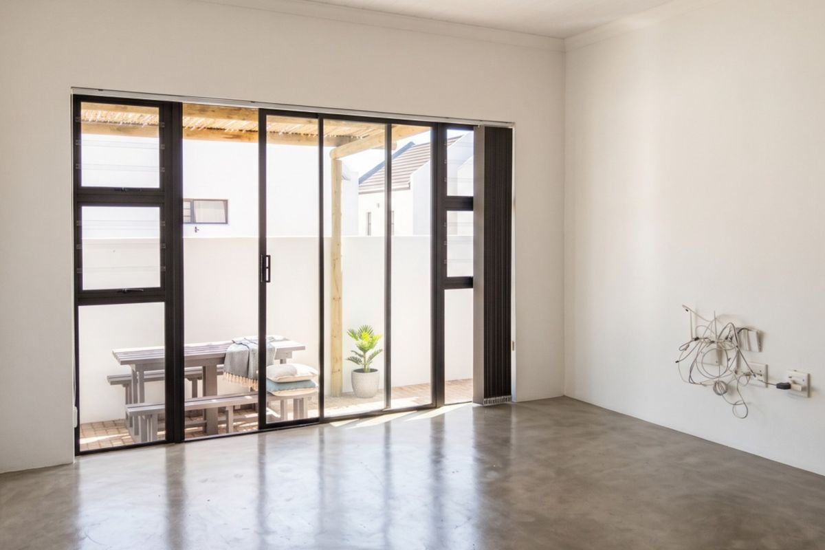 Bright and spacious living area featuring polished concrete floors and large sliding glass doors that open onto a private patio.