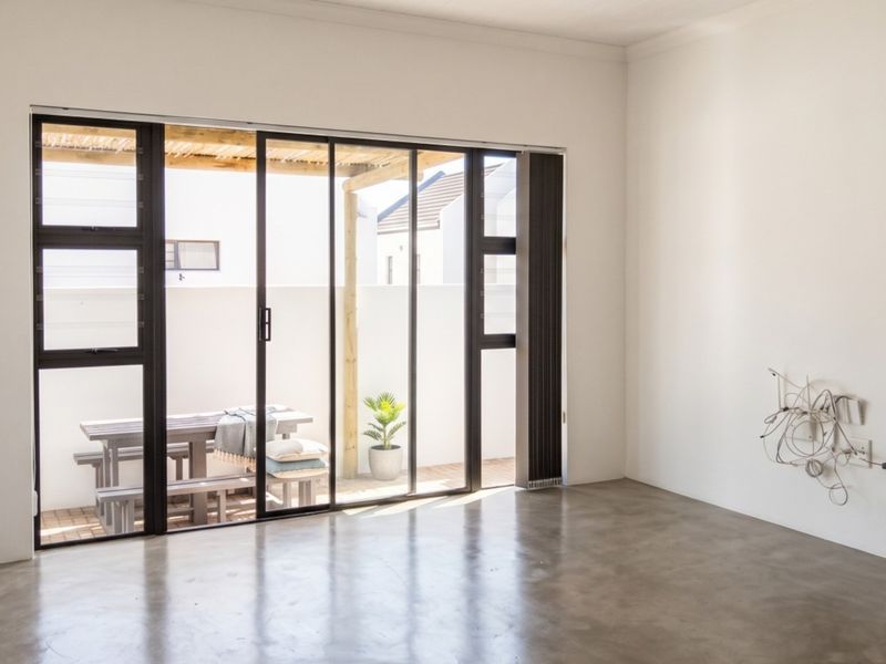 Bright and spacious living area featuring polished concrete floors and large sliding glass doors that open onto a private patio.