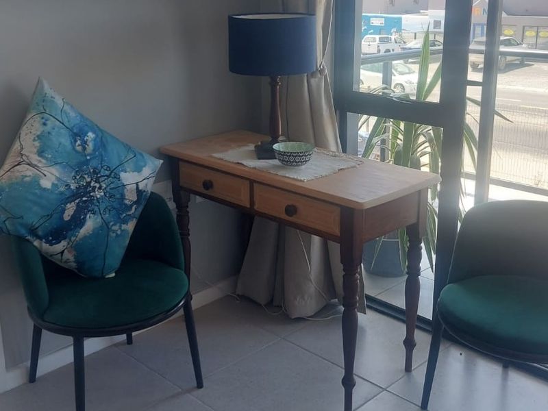 A bright living area featuring tiled flooring and a large glass sliding door providing access to a balcony with a metal railing.