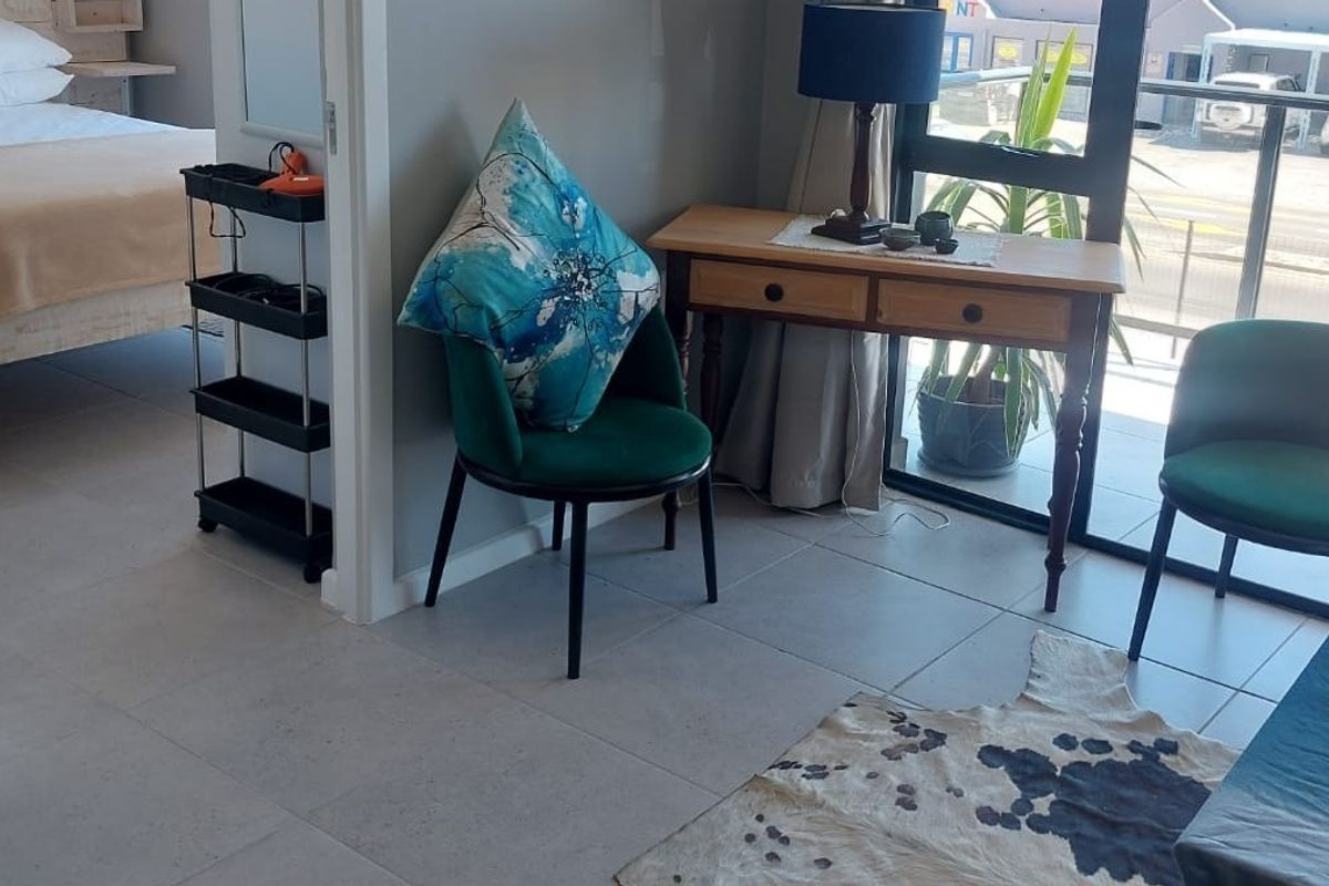 A bright living area featuring neutral tiled flooring and a large sliding glass door providing access to an outdoor balcony space.