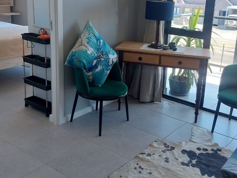 A bright living area featuring neutral tiled flooring and a large sliding glass door providing access to an outdoor balcony space.
