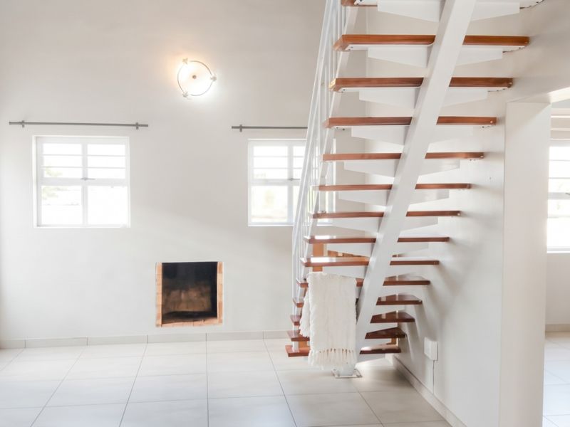 Bright and airy living area featuring an open-tread staircase, built-in fireplace, and neutral tiled flooring throughout.