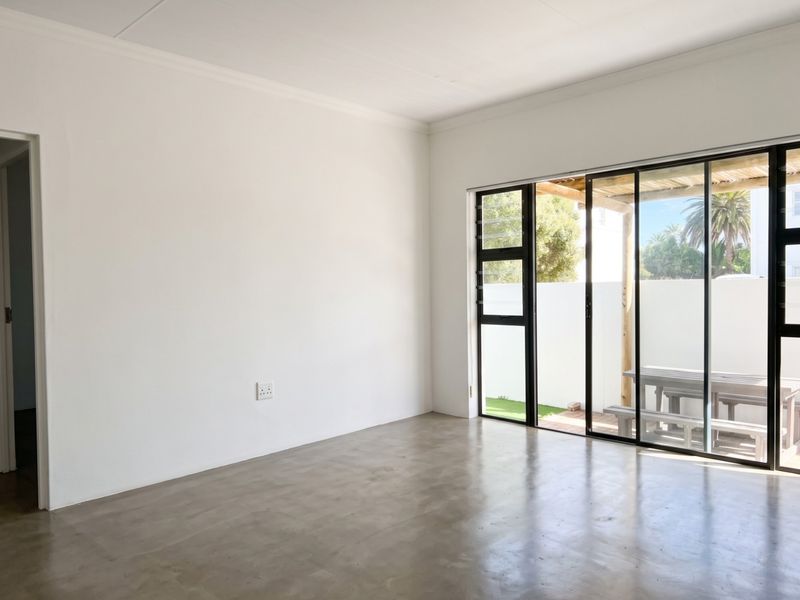 Bright and spacious living area featuring polished concrete floors and large sliding glass doors that provide seamless access to the outdoor patio.