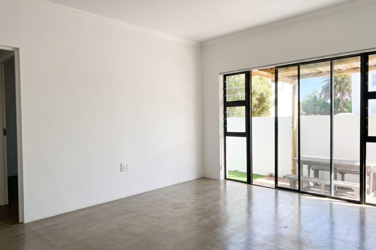 Bright and spacious living area featuring polished concrete floors and large sliding glass doors that provide seamless access to the outdoor patio.