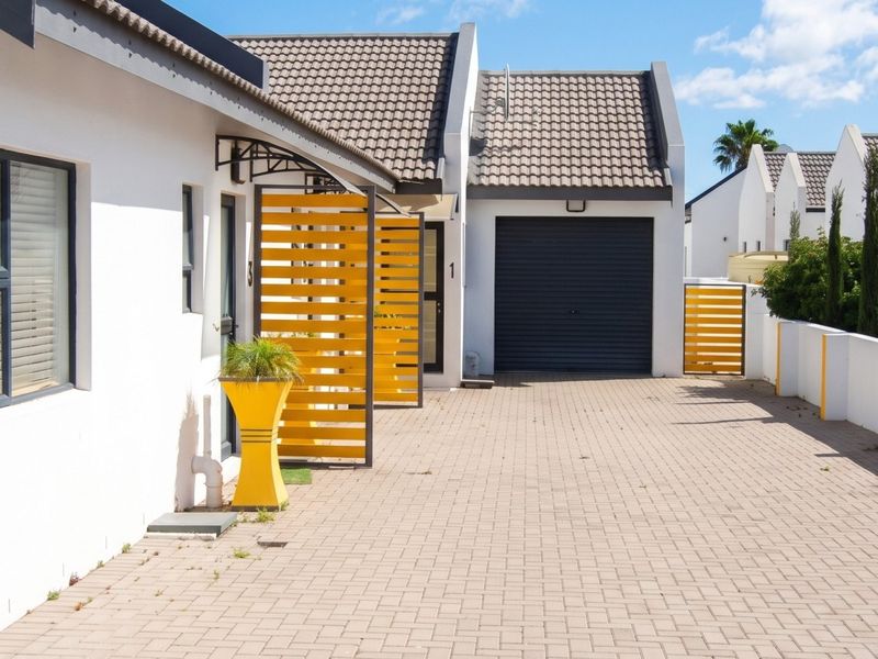 Front exterior view of a residential property featuring a paved driveway, garage, and modern architectural details including timber privacy screens and an outdoor shower.