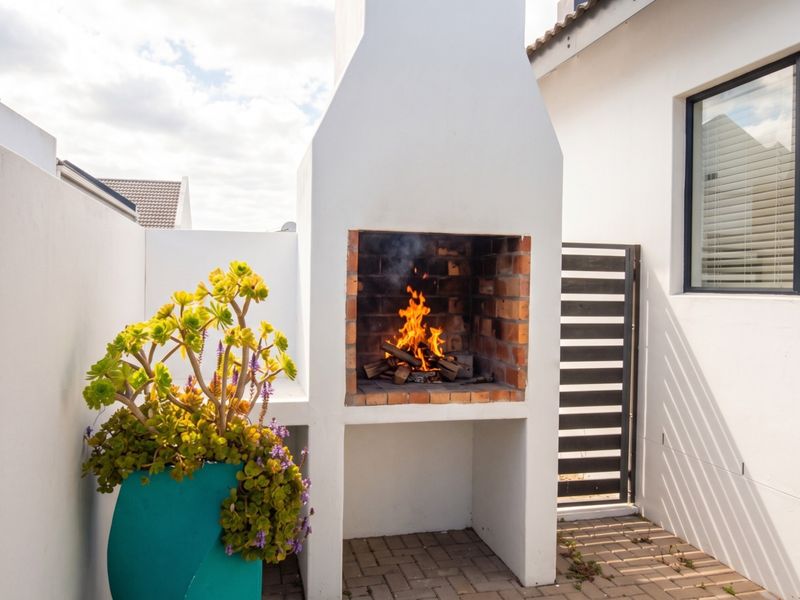 A private outdoor patio area featuring a built-in brick braai and paved flooring, ideal for outdoor entertaining.