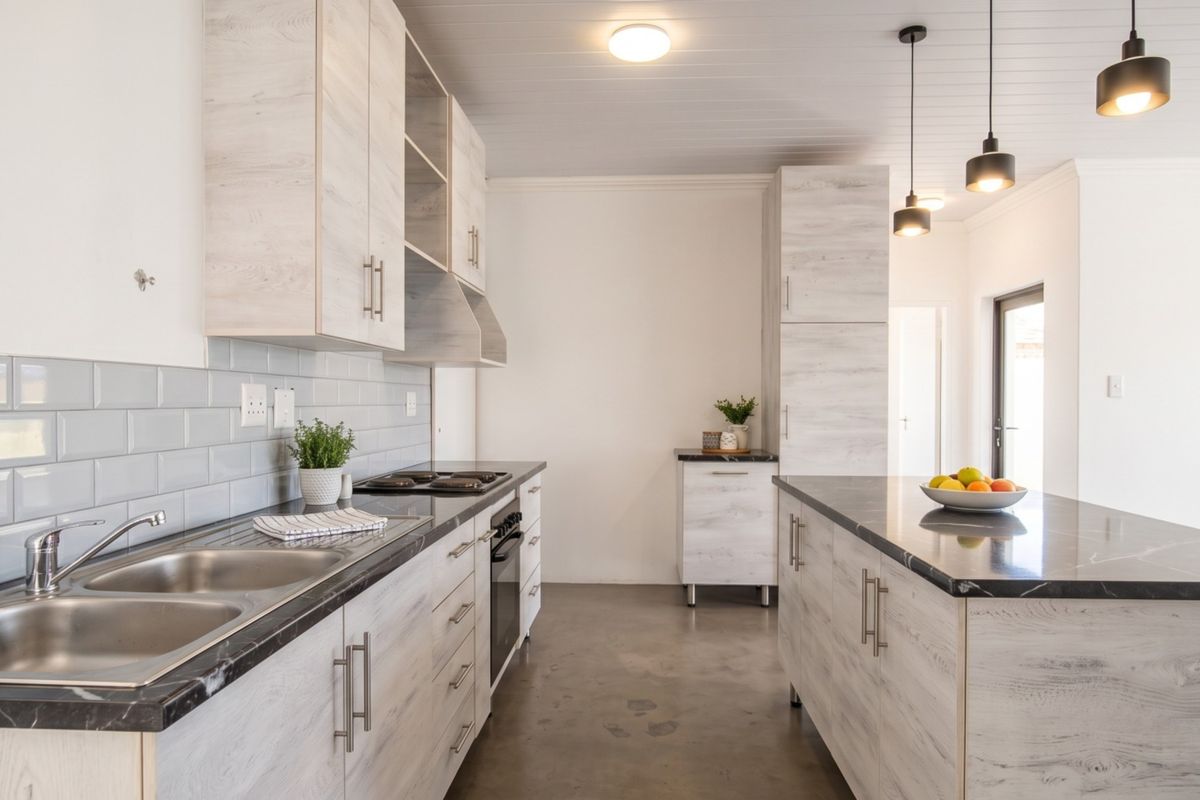 Modern kitchen featuring light wood-grain cabinetry, stone countertops, a central island, subway tile backsplash, and polished concrete flooring with contemporary pendant lighting.