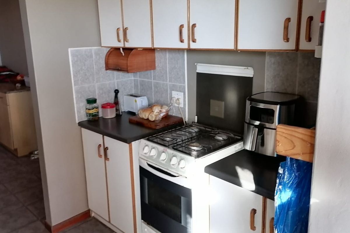 A compact kitchen featuring built-in cabinetry, a gas stove with oven, and tiled splashbacks, offering a functional layout for meal preparation.