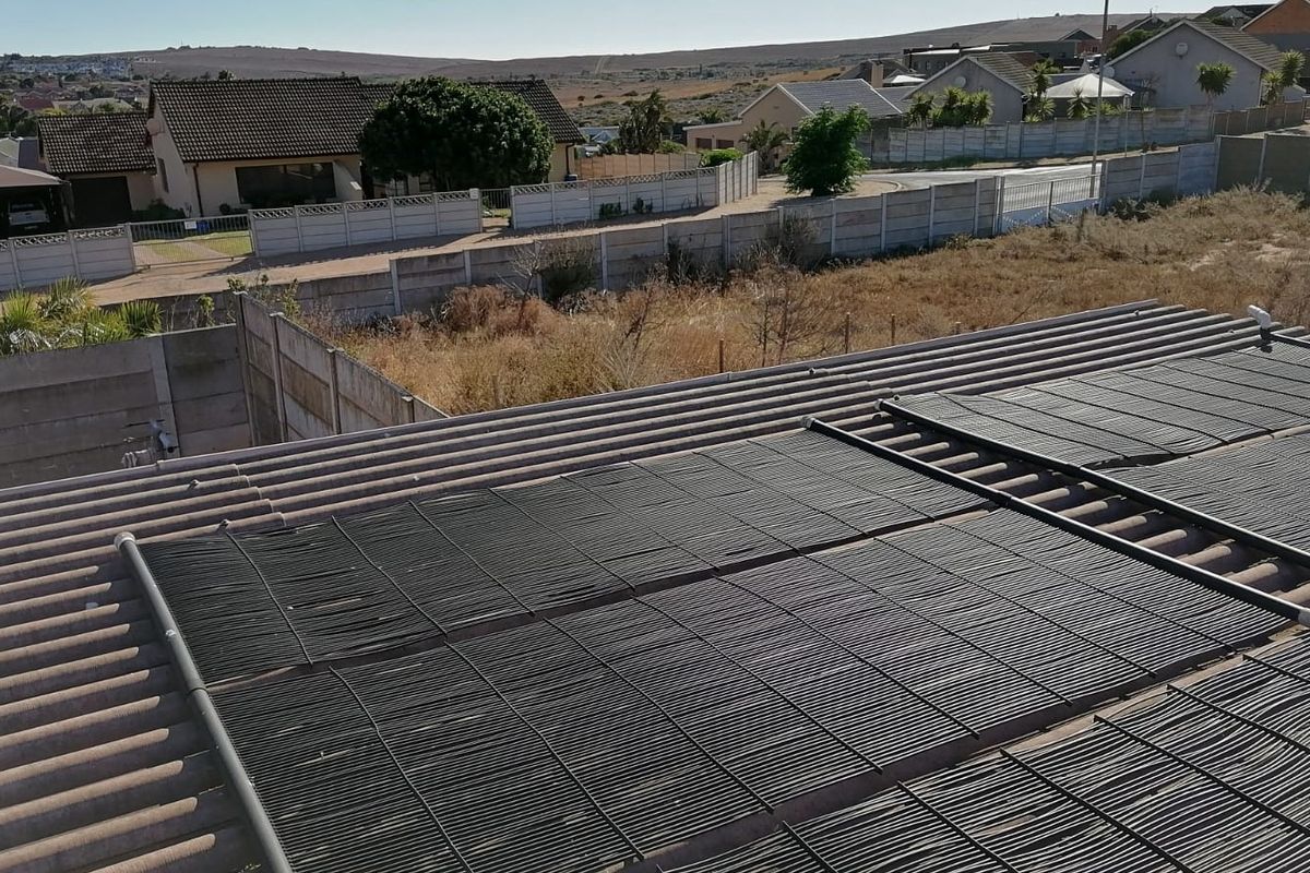 An elevated view of the property roof featuring installed solar pool heating panels, overlooking the surrounding residential neighbourhood.