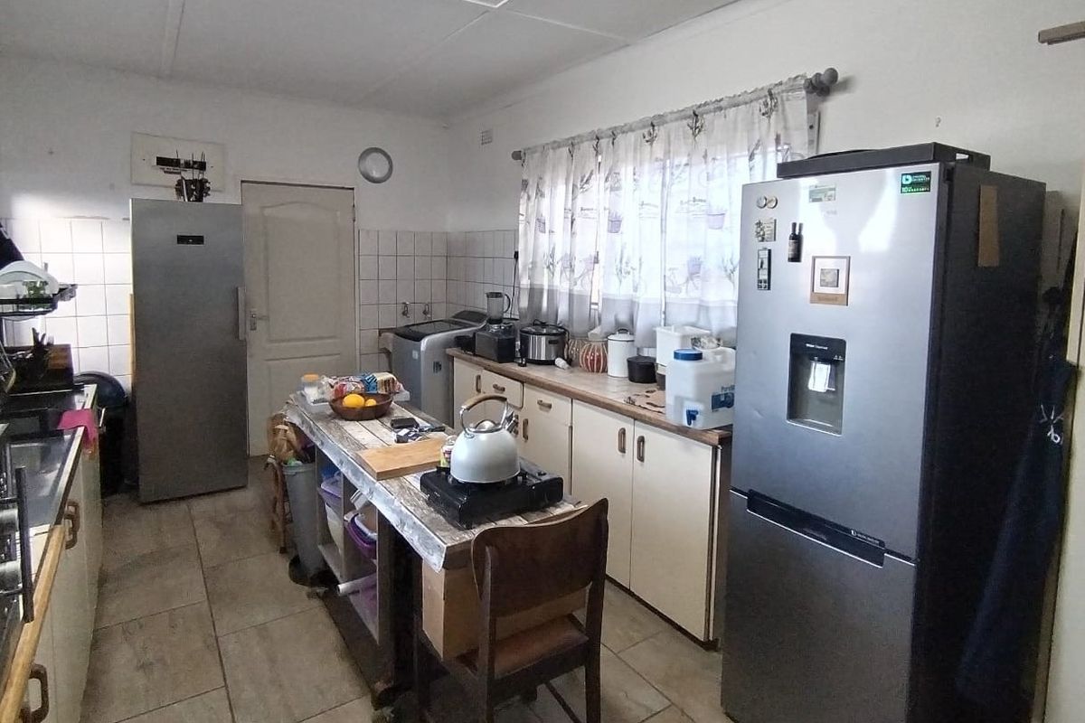 A functional kitchen featuring laminate countertops, tiled splashbacks, and ample cabinetry, providing a practical workspace for daily meal preparation.