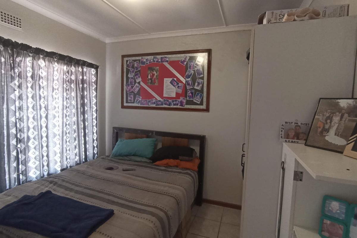 A functional bedroom featuring tiled flooring, a built-in wardrobe, and a window with curtain treatments.