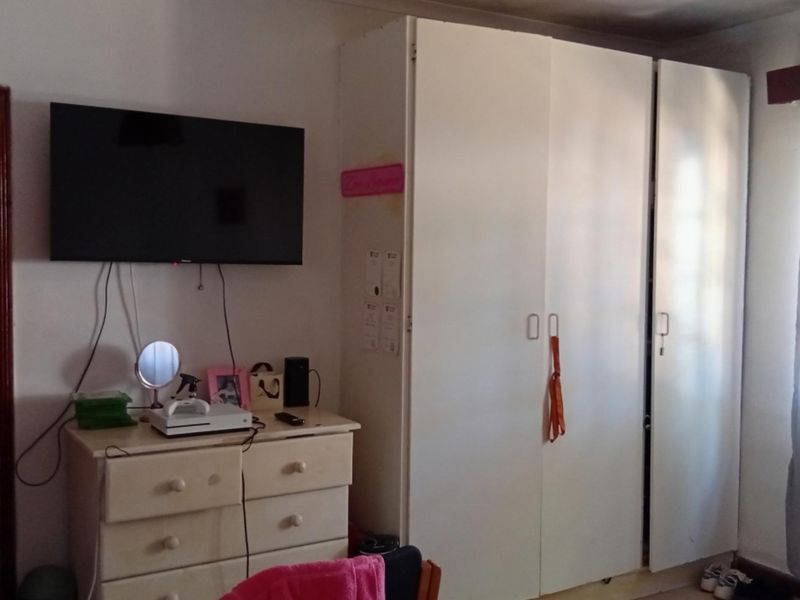 A bedroom featuring a built-in wardrobe and a timber door frame, providing functional storage space within the room.