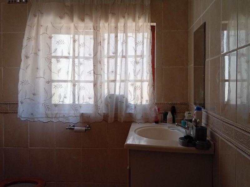 A functional bathroom featuring tiled walls, a vanity cabinet with a basin, a toilet, and a shower enclosure.