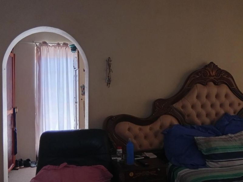 A bedroom featuring a built-in wardrobe and an arched doorway leading to an adjacent space.