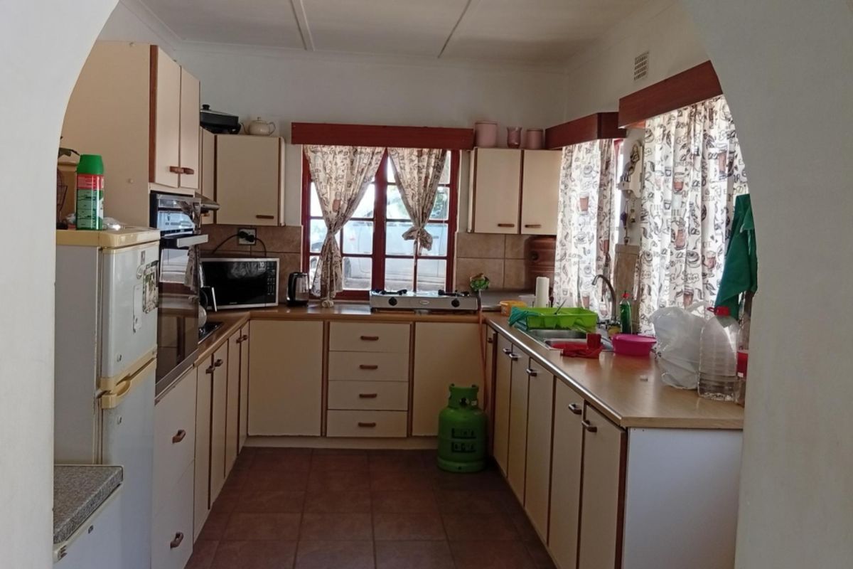 A functional kitchen featuring built-in cabinetry, laminate countertops, and a double sink, offering a practical layout with potential for modern updates.
