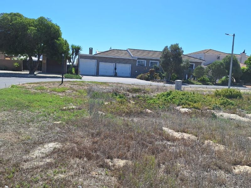A view of a vacant residential plot situated in a developed neighbourhood with established street access and surrounding homes.