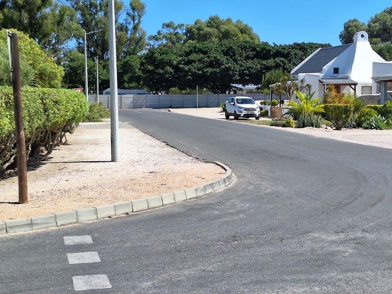 A view of the paved street and curb infrastructure leading towards the residential property entrance.