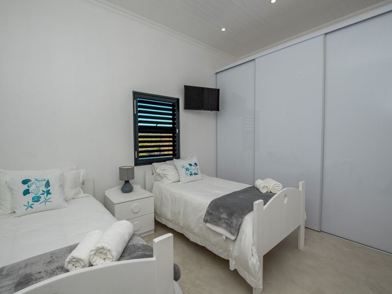 A clean, well-maintained bedroom featuring a large built-in wardrobe, louvered window, and modern recessed ceiling lighting.